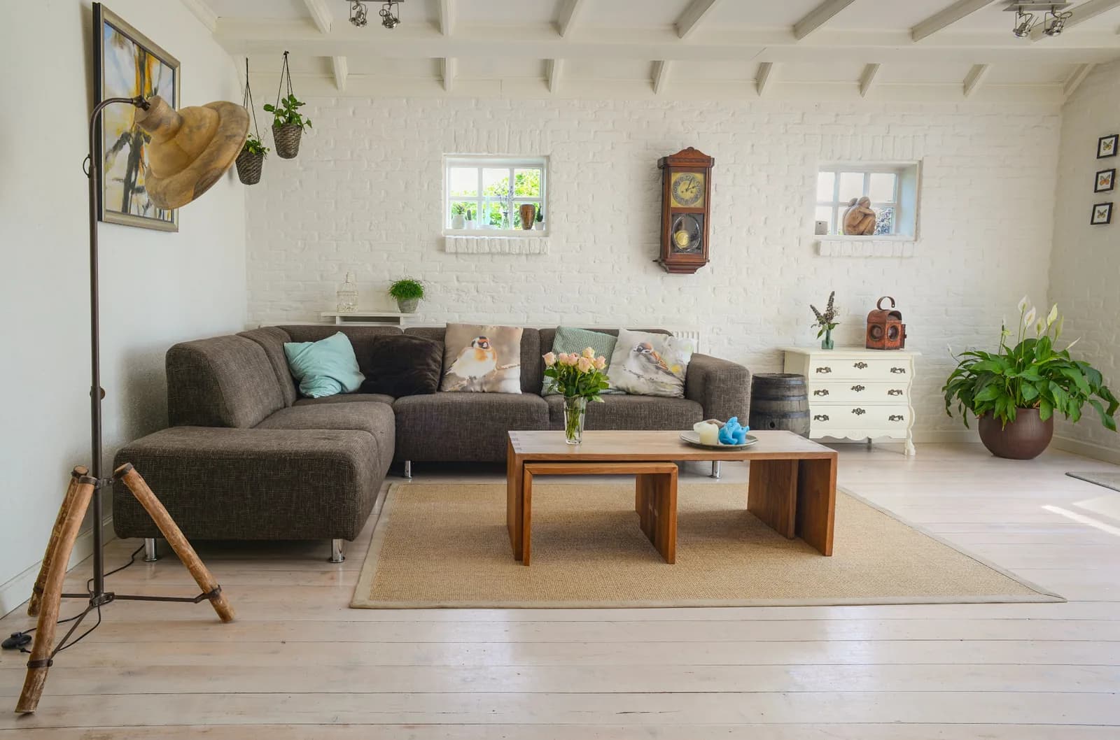 Salon lumineux avec canapé, table basse en bois et murs en briques peintes en blanc.
